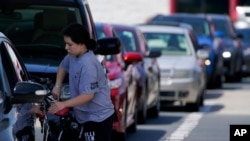 A customer pumps gas at Costco, as others wait in line, in Charlotte, N.C., May 11, 2021.